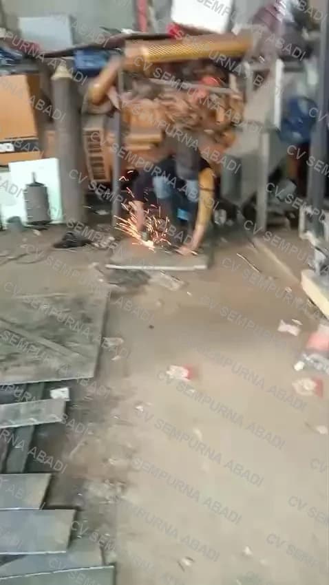 Memotong pelat besi dengan gerinda di lantai bengkel